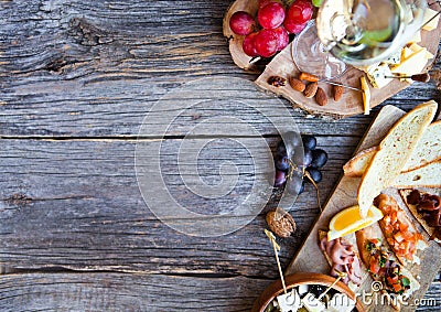 Glass with white wine, grape, cheese, over rustic wooden background. Wine snack set. Stock Photo