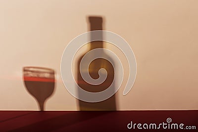 A glass of wine and a bottle casts a long shadow from the evening sun Stock Photo