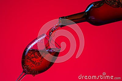 Glass of Wine and Bottle with Pouring Out Liquid. Against Red Stock Photo