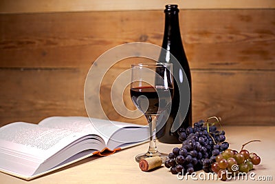 A glass of wine with grapes, bottle and an open book Stock Photo
