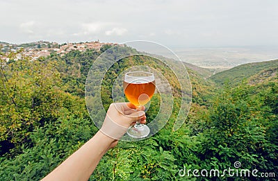 Glass of wine in hand of tourist in natural landscape of green Alazani Valley, Georgia. Homemade beverage Stock Photo