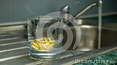 A glass with yellow gold colored capsules Stock Photo