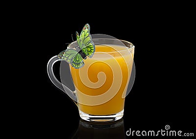 Glass with yellow juice and green butterfly on a handle on a black background Stock Photo