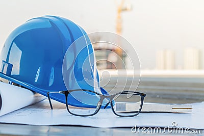 The glasses and blue safety helmet at construction site with crane background Stock Photo