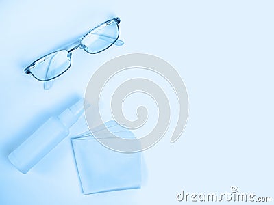 Glasses care product. Glasses, spray, napkin for glasses on light background. Blue monochrome background. Ophthalmology Stock Photo