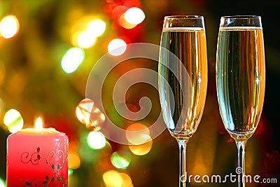 Glasses with champagne and candle against festive lights Stock Photo