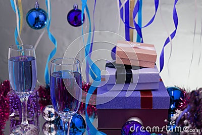 glasses with champagne on a wooden table with Christmas red balls, a glossy ribbon with a sprig of spruce on the backg Stock Photo
