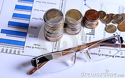 Glasses and coins on financial graphics Stock Photo