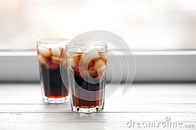 Glasses of cola with ice near window Stock Photo