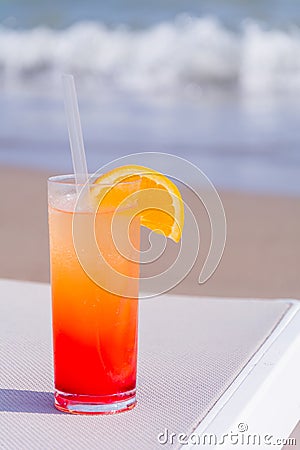 Glasses with colored cocktails on the beach with blue water Stock Photo