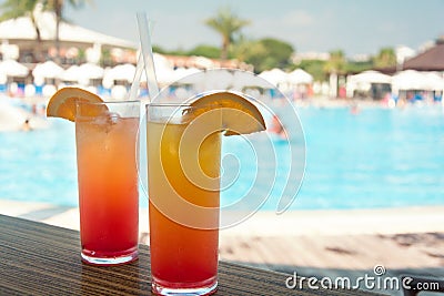 Glasses with colored cocktails on the side of a swimming pool Stock Photo