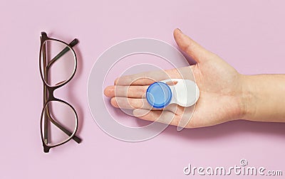 Glasses and contact lens case in human hand on purple background. Concept of choice the way vision correction Stock Photo