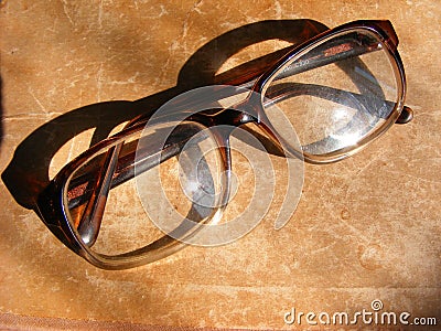 Reading glasses and old book, glasses on aged shabby background Stock Photo