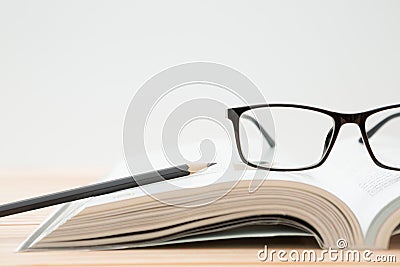 Glasses, open book, pencil on wooden table, white background and copy space Stock Photo