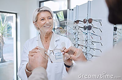 Glasses, retail store and sale of a senior eye doctor holding a frame to help customer shopping. Happy optometrist, shop Stock Photo