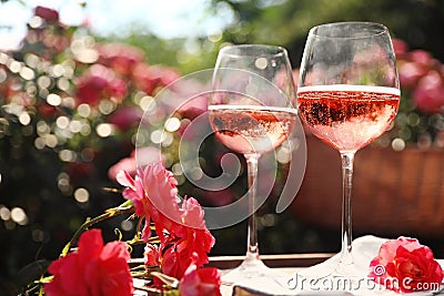 Glasses of rose wine on table in blooming garden Stock Photo