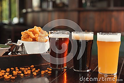 Glasses of tasty beer and snacks on wooden table Stock Photo