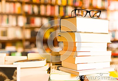 Glasses on top of stack of books lying on table in bookstore Stock Photo