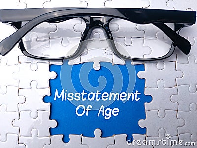 Glasses and white puzzle with the word Misstatement Of Age Stock Photo