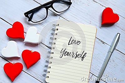 Glasses,wooden heart,pen and notebook written with Love Yourself. Stock Photo