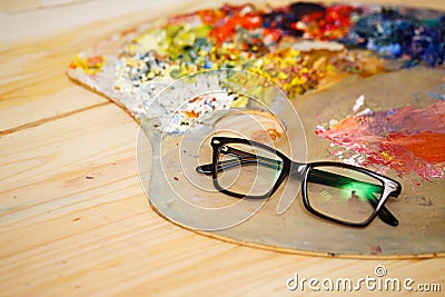 Glasses, wooden palette and oil paints Stock Photo