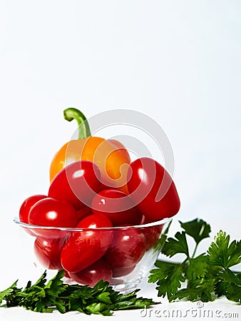 Glasss cup with tomatoes and peppers on a white table with parsley. Stock Photo