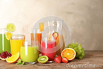 Glassware with different juices and fresh fruits on table Stock Photo