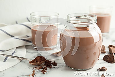 Glassware with tasty chocolate milk on marble table. Stock Photo