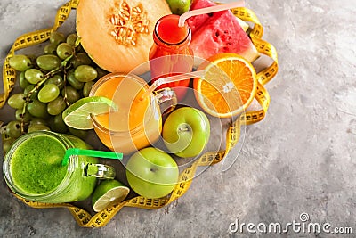 Glassware of tasty smoothies with measuring tape on grey table. Diet concept Stock Photo