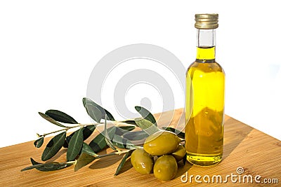 Glassy bottle of olive oil with group of green shiny olives and brunches with leafs Stock Photo