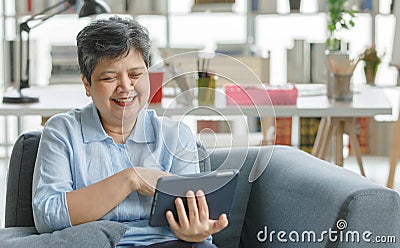 Gleeful Asian female using tablet at home Stock Photo