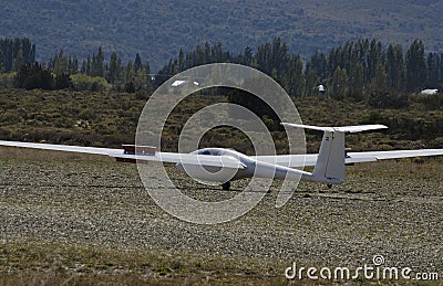 Glider ultralight plane flying near mountains, landing on earth aerodrome Stock Photo