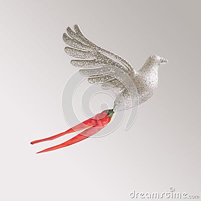 Glitter toy dove with fresh bird eye chillies against light gray background. Modern minimal abstract concept Stock Photo