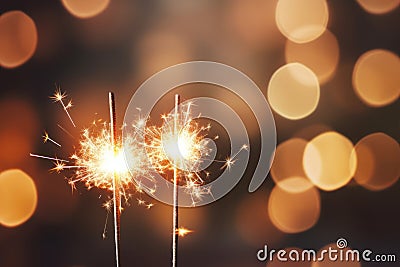 Glittering burning sparklers against blurred colorful bokeh background. Celebrating Christmas and New Year's Eve Stock Photo