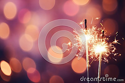 Glittering burning sparklers against blurred colorful bokeh background. Celebrating Christmas and New Year's Eve Stock Photo