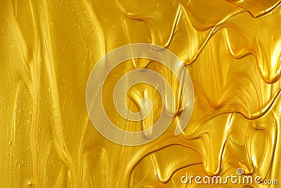 Glittering shiny metallic gold paint flowing and dripping downward making a golden background with empty copyspace Stock Photo