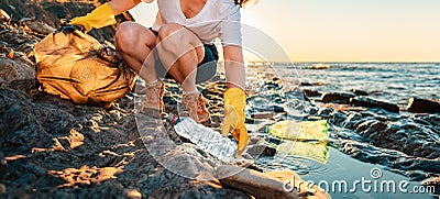 Global environmental pollution banner. A female volunteer sitting collects plastic bottles on the ocean shore. Cleaning Stock Photo