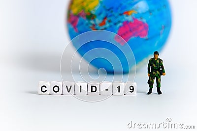 Miniature soldier stands in front of earth globe and word beads Stock Photo