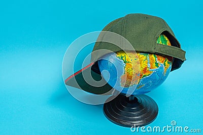 Globe with a green baseball cap on it on a blue background Stock Photo