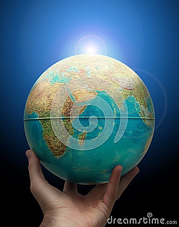 Globe in hand with rising sun Stock Photo