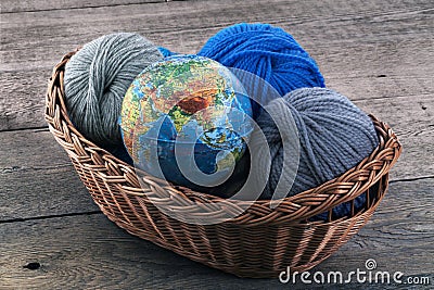 Globe and skeins of yarn in a wicker basket Stock Photo