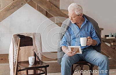 Gloomy aged man looking at the chair near him Stock Photo