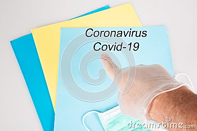 Glove plastic hand pointing finger on Novel coronavirus disease coid-19 virus written on blue folder on hospital desk Stock Photo