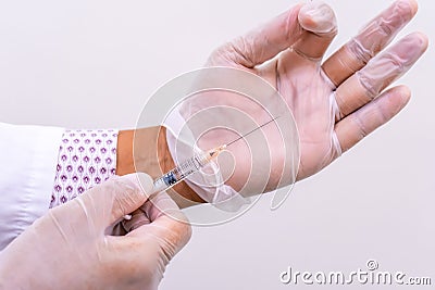 Gloved doctor hands holding an injection vial of a hyaluronic acid HA based dermal filler for anti-aging and volumizing face Stock Photo