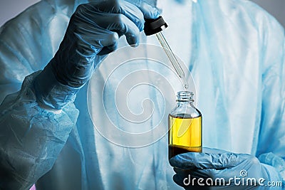 Gloved doctor hands with pipette dropping liquid substance into transparent bottle, clinical trials, analyzes and samples, cosme Stock Photo