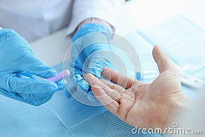 Gloved doctor takes blood test with lancet from patient at clinic Stock Photo