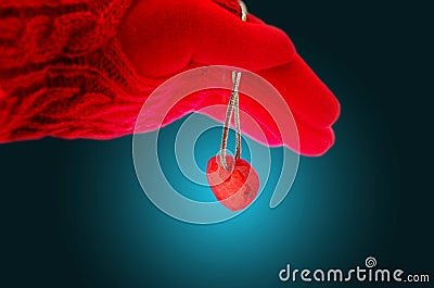 A gloved hand gently holds a red glass heart. Image Stock Photo