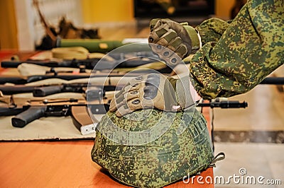 A gloved hand on a military helmet, hand clenched into a fist against the background of weapons Editorial Stock Photo