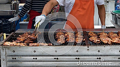 Gloved hand turning meat grilling on large BBQ Stock Photo