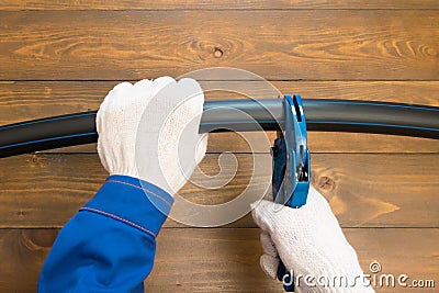 Gloved hands cut a black pipe with special scissors for cutting plastic Stock Photo